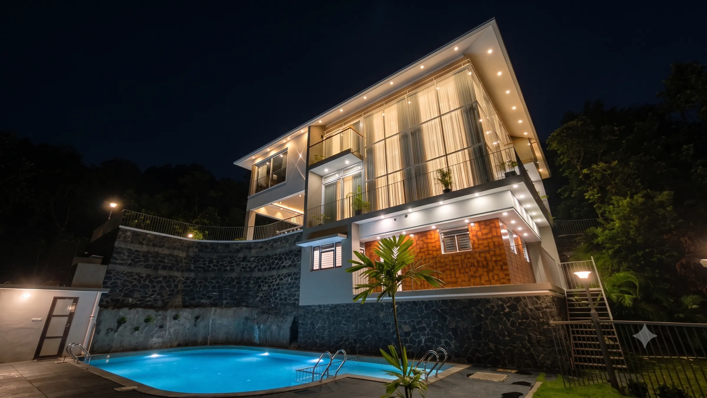 The mansion lit after dark above the private pool